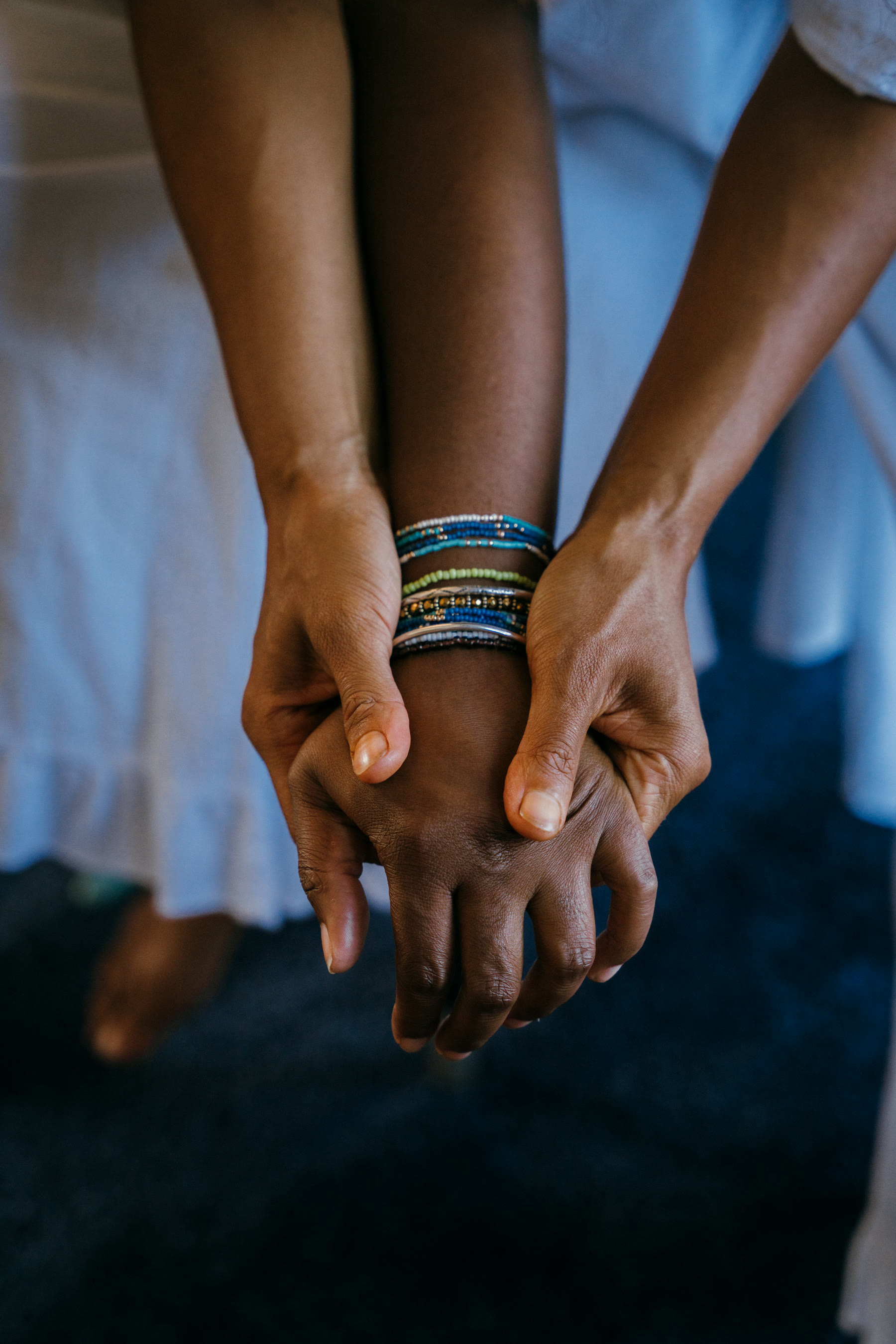 Two pairs of hands clasped together